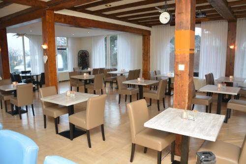 a dining room with tables and chairs and a clock at SEA YOU Hotel Noordwijk in Noordwijk aan Zee