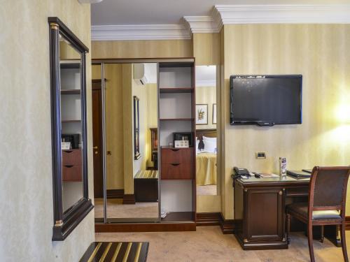a room with a mirror and a desk and a tv at La Gioconda Boutique Hotel in Odesa