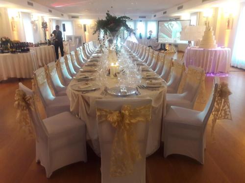 a long table with white tables and white chairs at Hotel In Sylvis in Sesto al Reghena