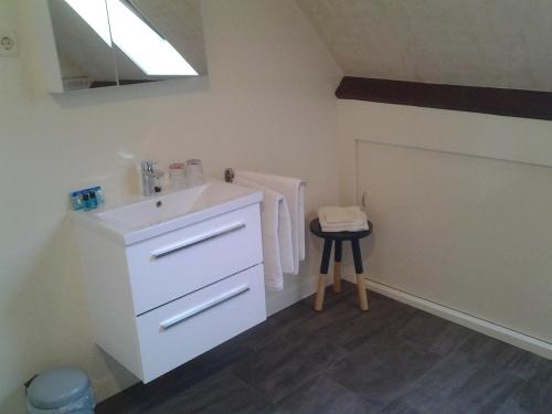 a white bathroom with a sink and a stool at Bed & Breakfast Meinsma in Moddergat