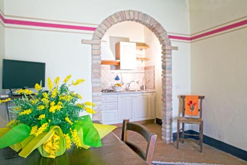 a dining room with a table with a vase of yellow flowers at Residenza Storica Casale Pozzuolo in Cinigiano