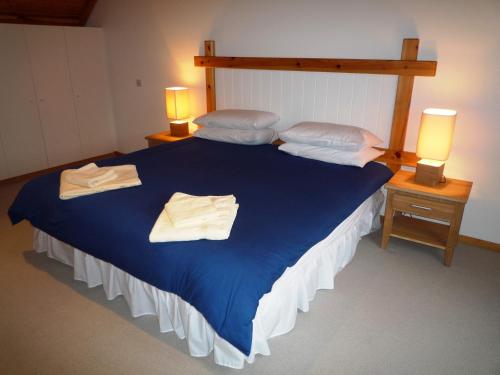 Un dormitorio con una cama azul con toallas. en Waterville Holiday Homes No 1 en Waterville