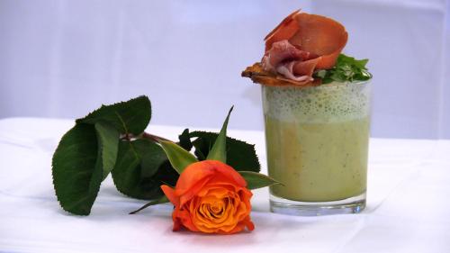 a drink with a sandwich on top of it next to flowers at Hotel Schwarzenbergs Traube in Glottertal