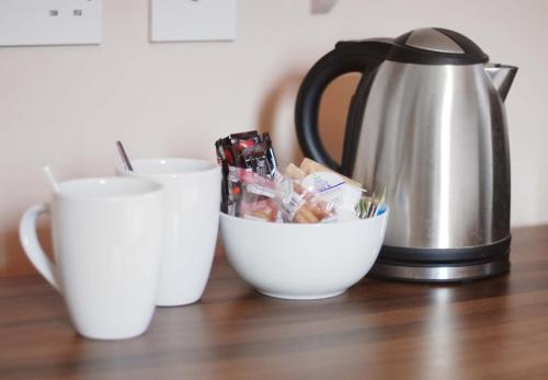 a tea kettle and cups on a wooden table at Waverley Hotel in Peterhead