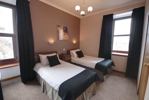 a hotel room with two beds and two windows at Waverley Hotel in Peterhead