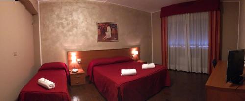 a hotel room with two beds and a television at Hotel Forum in Rozzano