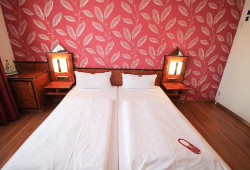 two beds in a room with red wallpaper at Hotel Miramar am Römer in Frankfurt/Main