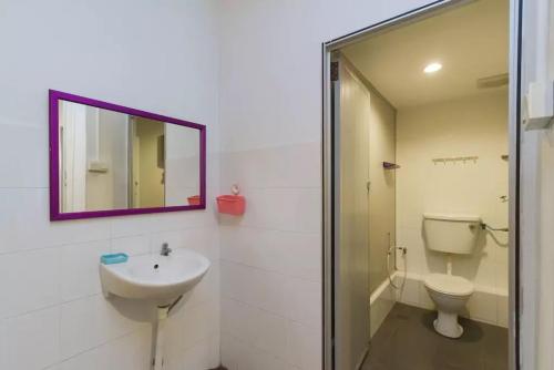 a bathroom with a sink and a toilet and a mirror at Cocoa Mews Cafe and Homestay in George Town