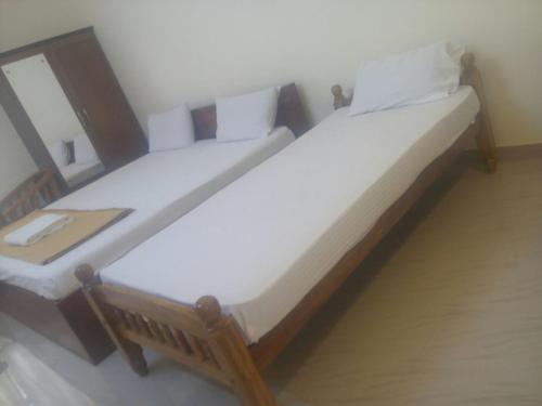 a pair of beds in a room with at Manjira Lodge in Guruvāyūr
