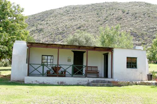 a small white house with a mountain in the background at Kranskloof Country Lodge in Oudtshoorn