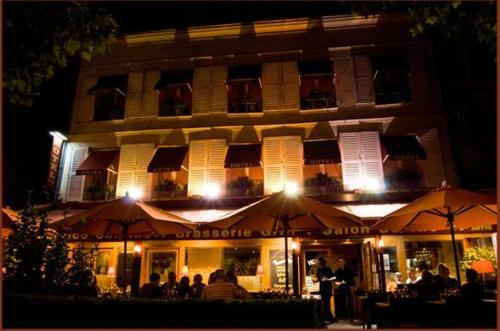 a restaurant with umbrellas in front of a building at night at Hotel l'Avenue in Chantilly