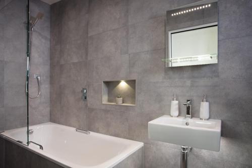 bagno con vasca, lavandino e specchio di Wooda Farm Holidays a Bude