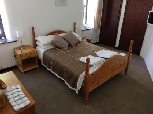 a bedroom with a large wooden bed with pillows at The Old Piggeries in Gulval