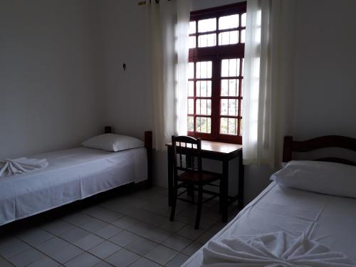 a bedroom with two beds and a desk and a window at Pousada Convento da Conceição in Olinda