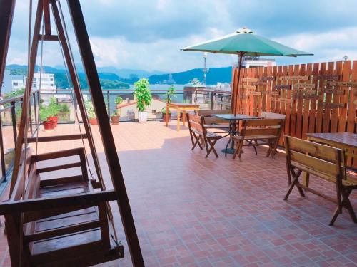a patio with tables and chairs and an umbrella at Sun Moon Lake Tan Hsiang Yu B&B in Yuchi