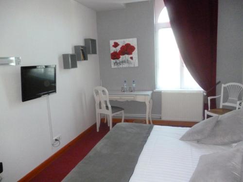 a bedroom with a bed and a table and a television at Hôtel Picardia in Saint-Valery-sur-Somme
