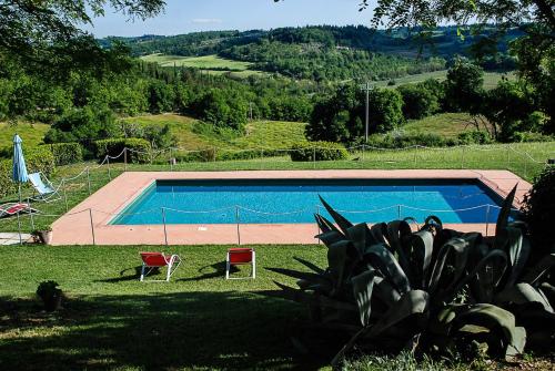 una piscina en un patio con 2 sillas en Bio-Agriturismo La Ginestra en San Casciano in Val di Pesa