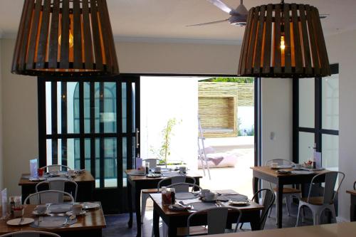 a dining room with tables and chairs and large windows at Whale Rock Luxury Lodge in Hermanus