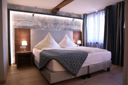 a bedroom with a large bed with white sheets and pillows at Markthotel Warendorf in Warendorf