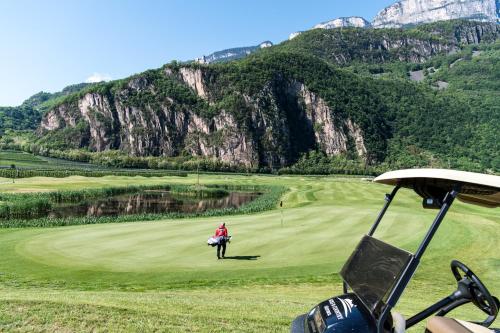 a person on a golf course with mountains in the background at Hotel Christof in Appiano sulla Strada del Vino
