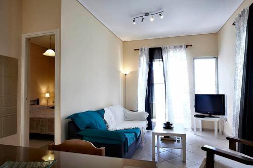 a living room with a blue couch and a television at Sunday Apartments in Nafplio