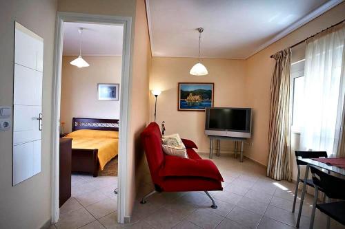 a bedroom with a red chair and a bed and a television at Sunday Apartments in Nafplio