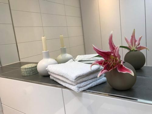 eine Badezimmertheke mit Vasen, Handtüchern und einer Blume in der Unterkunft Nauwieser50 in Saarbrücken