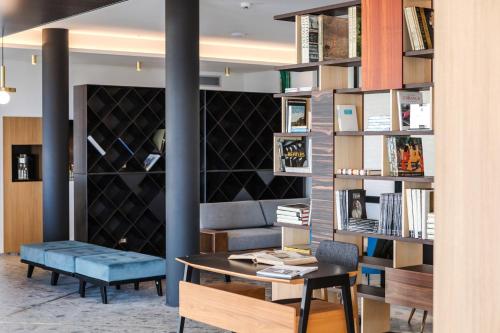 a library with a table and a couch and bookshelves at MaisonMe Boutique Hotel in Bardolino