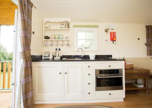 a kitchen with white cabinets and a sink at The Hideaway Huts in Bardon Mill