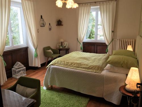 a bedroom with a bed and a chair and windows at La Maison du Parc in Yzeron