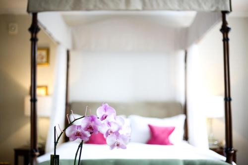 a bedroom with a bed with pink and white pillows at Ockenden Manor Hotel & Spa in Cuckfield