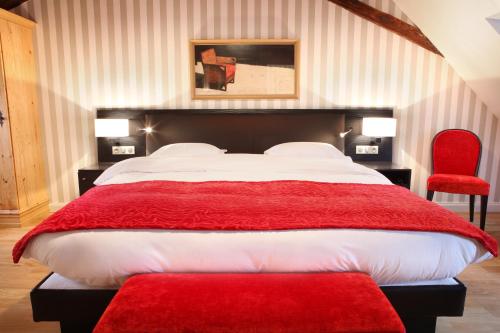 a bedroom with a large bed and a red chair at Logis Hôtel Ettenheim in Strasbourg