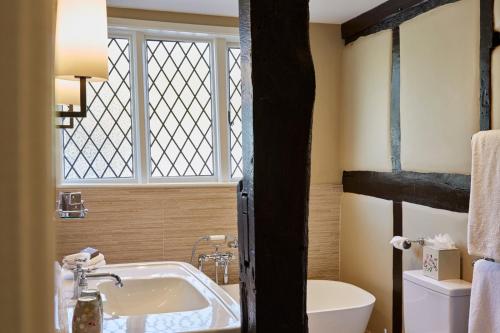 a bathroom with a tub and a toilet and a window at Ockenden Manor Hotel & Spa in Cuckfield
