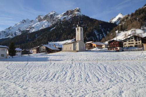 a small church in a snow covered village with mountains at Hotel Seeblick in Sufers