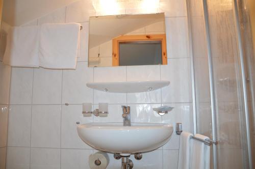 a bathroom with a white sink and a mirror at Hotel Seeblick in Sufers