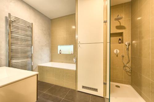 uma casa de banho com um chuveiro, uma banheira e um lavatório. em Spacious And Bright Apartment Dusni 13 em Praga