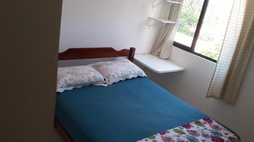 - une chambre avec un lit doté d'un couvre-lit bleu et d'une fenêtre dans l'établissement Edificio Paris, à Maceió