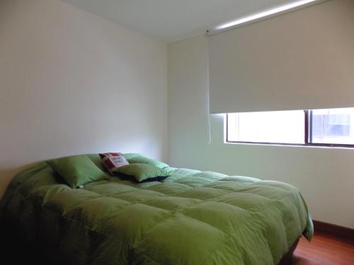 1 dormitorio con cama verde y ventana en Room and private Bathroom at Chapinero Alto, en Bogotá