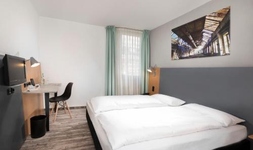 Habitación de hotel con 2 camas, escritorio y TV. en ibis Styles Hotel Gelsenkirchen en Gelsenkirchen