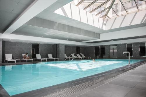 a large swimming pool in a building with a person sitting in chairs at Relais Spa Chessy Val d'Europe in Chessy