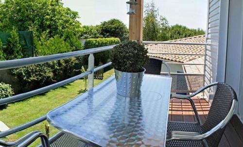 a glass table with a potted plant on a balcony at Le Clos des Romarins in Saint-Palais-sur-Mer