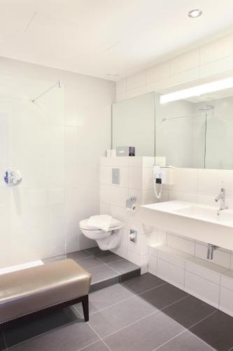 a white bathroom with a sink and a toilet at Logis Hôtel Ettenheim in Strasbourg