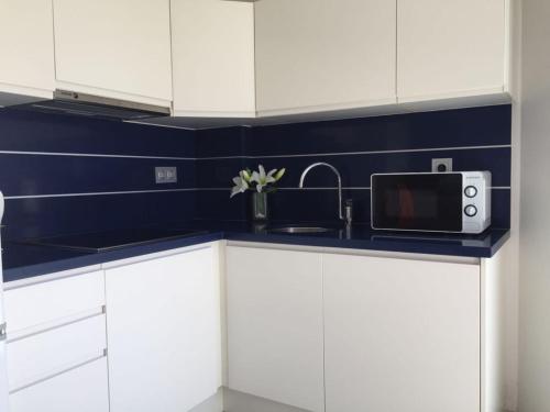 a kitchen with white cabinets and a sink and a microwave at Apartamentos Marjal 3 in Guardamar del Segura