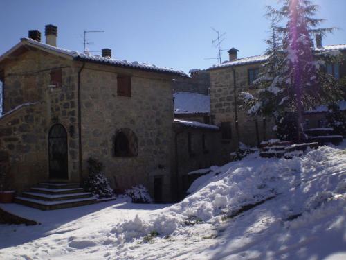 a building with snow on the ground in front of it at Il Borgo Del Lupo Relax Family Apartments in Tuscany with Restaurant & Swimming Pool in Sarteano