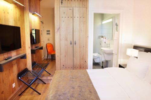 a bedroom with a bed and a television and a bathroom at Logis Hôtel Ettenheim in Strasbourg