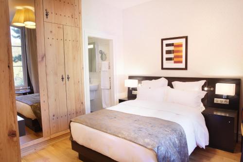 a bedroom with a large white bed and a bathroom at Logis Hôtel Ettenheim in Strasbourg