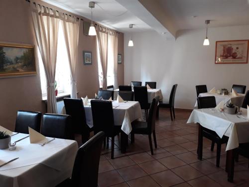 un comedor con mesas blancas y sillas negras en Hotel Restaurant Stern en Mannheim