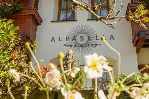 a sign on the side of a building with flowers at Alpasella Ferienwohnungen in Sankt Gallenkirch