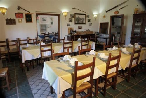 a restaurant with tables and chairs with yellow tablecloths at Agriturismo Sa Ruda in Càbras