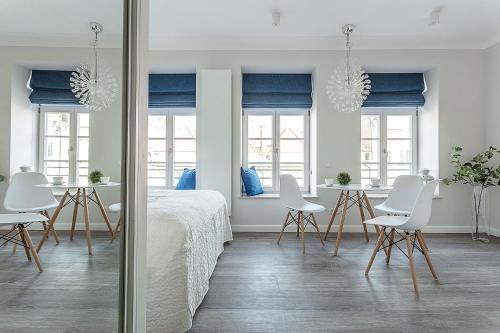 a bedroom with white furniture and a table and chairs at VIU Indigo Apartments in Gdańsk